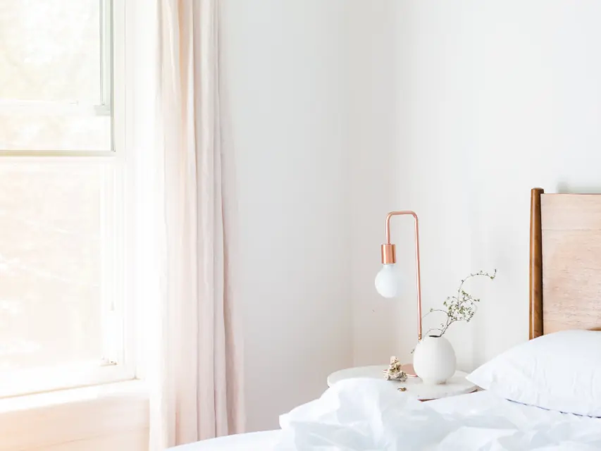 Chambre lumineuse avec lit blanc et lampe de chevet